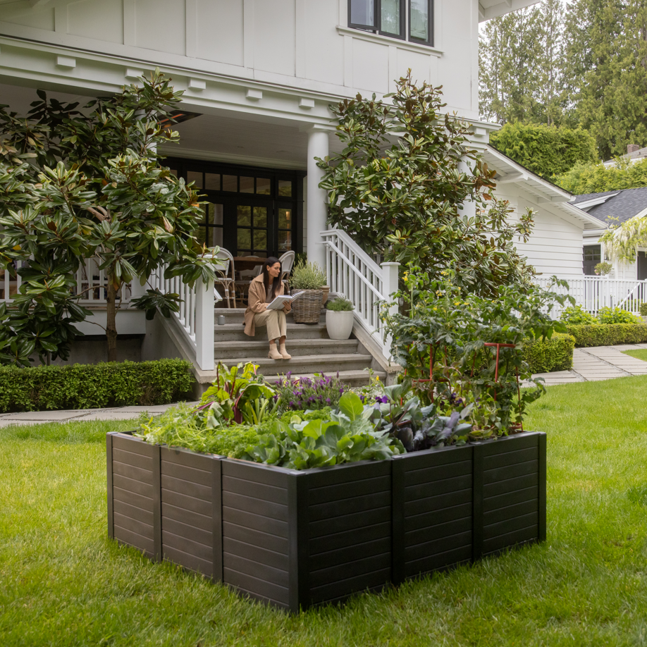 Person sitting on steps of a house with a garden bed in the foreground